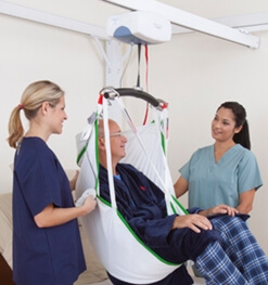 Man being helped in a ceiling lift by two nurses