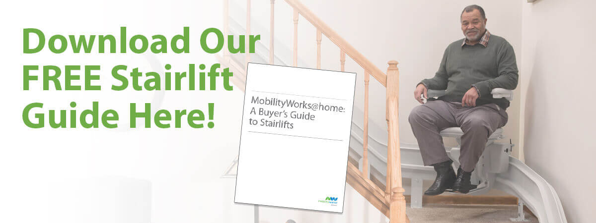 MW-Website-Banner-Desktop_White-Paper_Home-Access-1200-x-450 (1) A man sits on a stairlift near a staircase with a sign reading Download Our FREE Stairlift Guide Here! and a guide titled Mobilityworks@home: A Buyers Guide to Stairlifts.