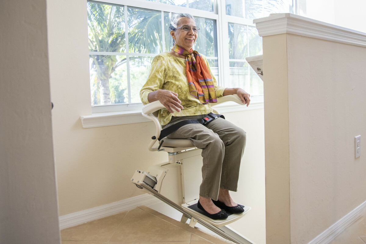 Woman on Harmar stairlift at top of stairs