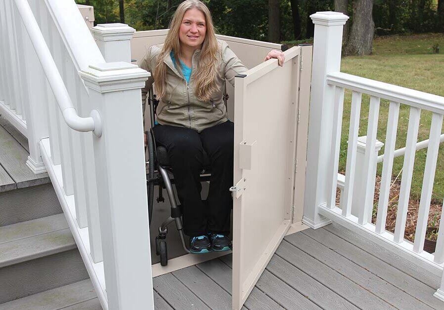 A woman in a wheelchair using an outdoor vertical platform lift