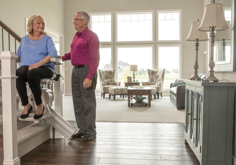 Woman on stair lift with man standing next to her